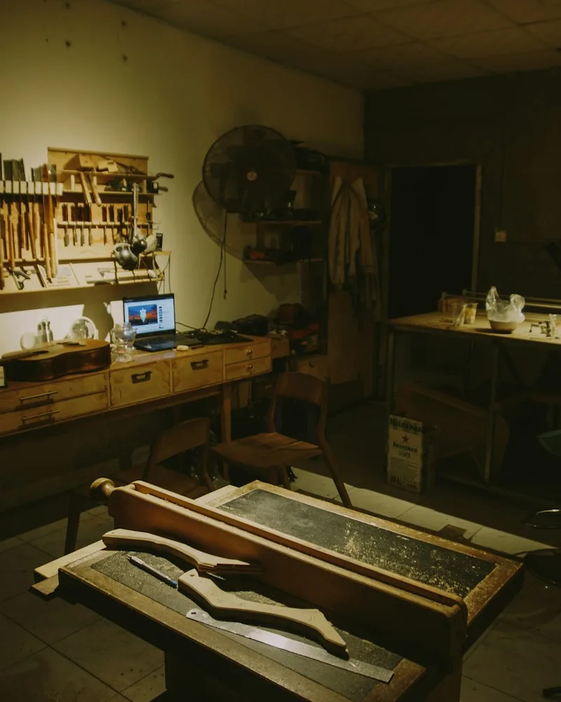 Herramientas de mano y piezas de madera sobre el banco de un taller en penumbra